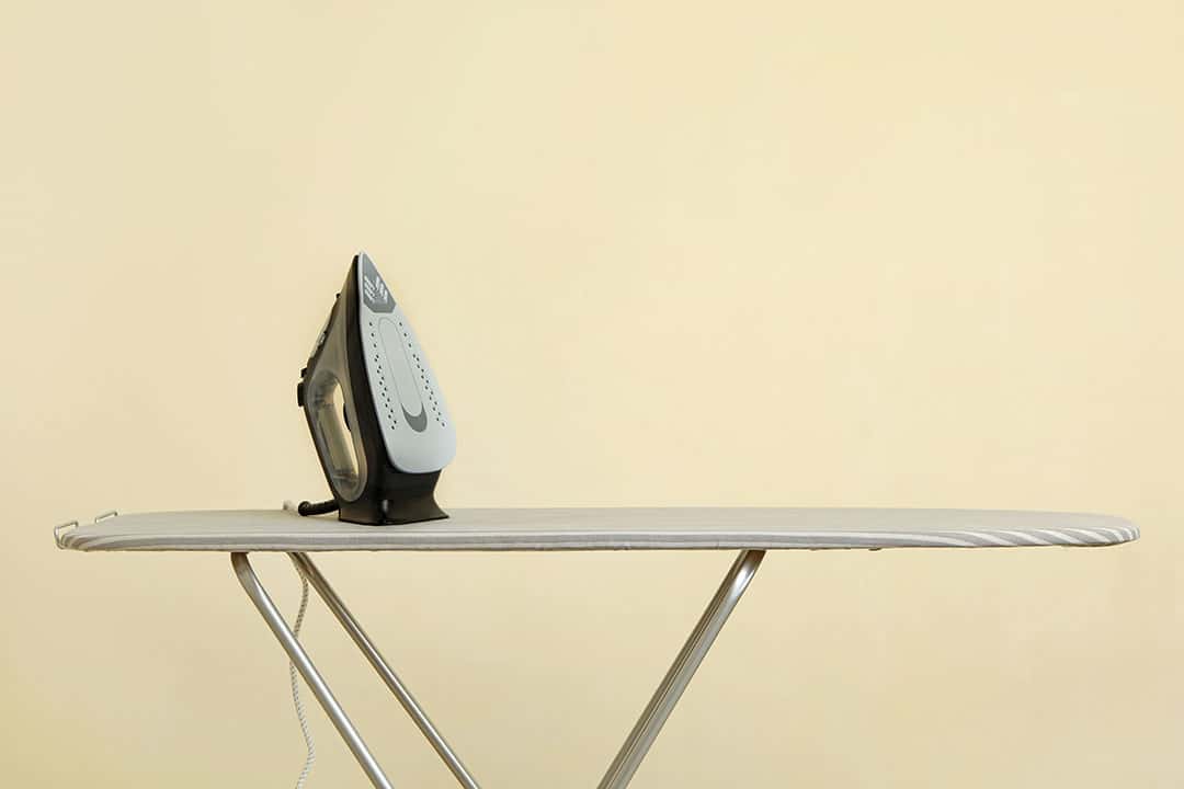 Fer à repasser moderne posé sur une planche à repasser