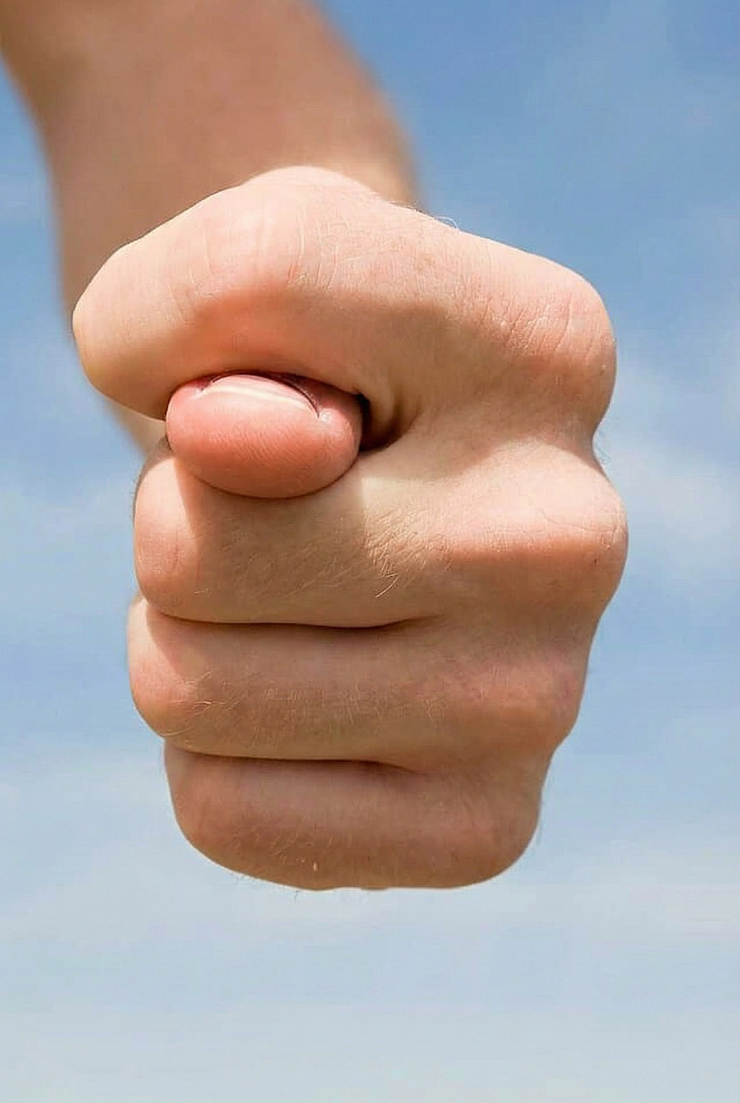 Main d'enfant formant le geste de la figue, sur fond coloré