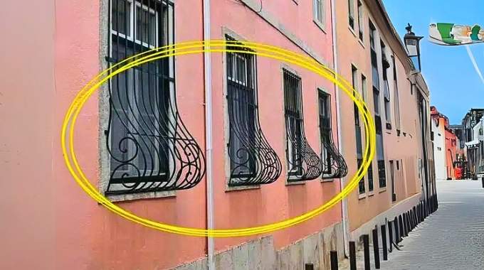 Détail d'une fenêtre avec des barreaux de fer forgé incurvés vers l'extérieur