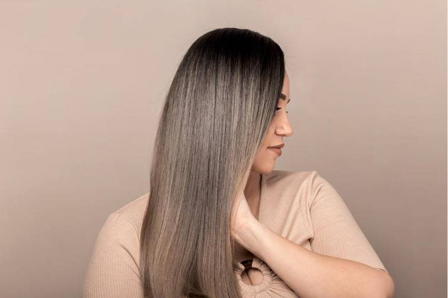 Femme aux cheveux longs et lisses, tenant une bouteille d'huile végétale