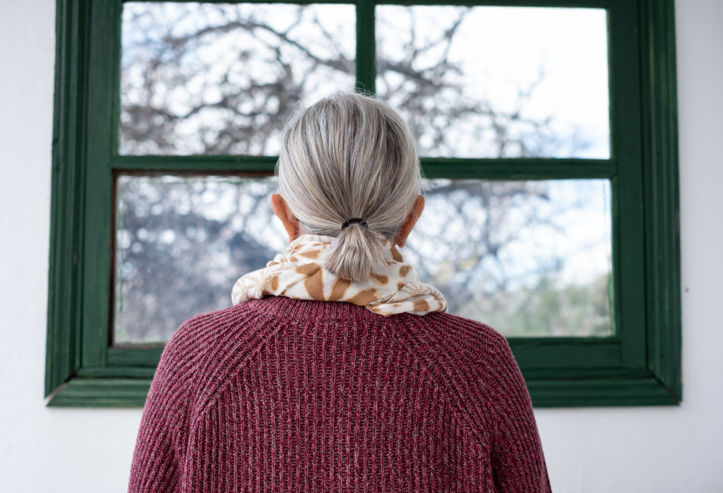 Femme aux cheveux gris regardant par la fenêtre