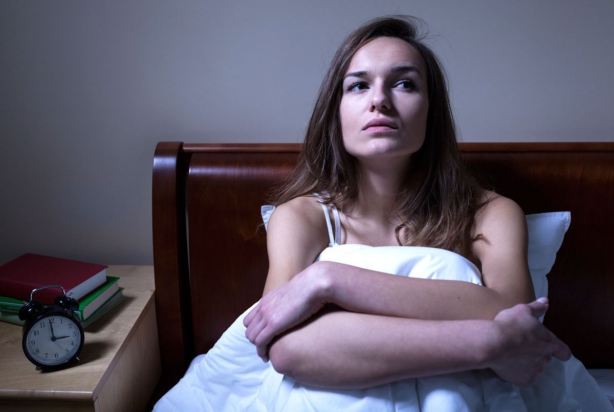 Femme réveillée la nuit regardant par la fenêtre