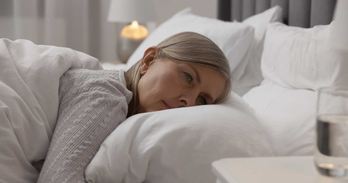Une femme buvant une tisane calmante le soir dans sa cuisine.
