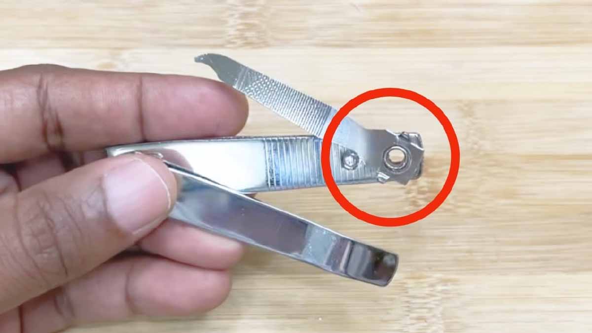 Personne tenant un coupe-ongles, le doigt positionné sur le trou pour une meilleure prise