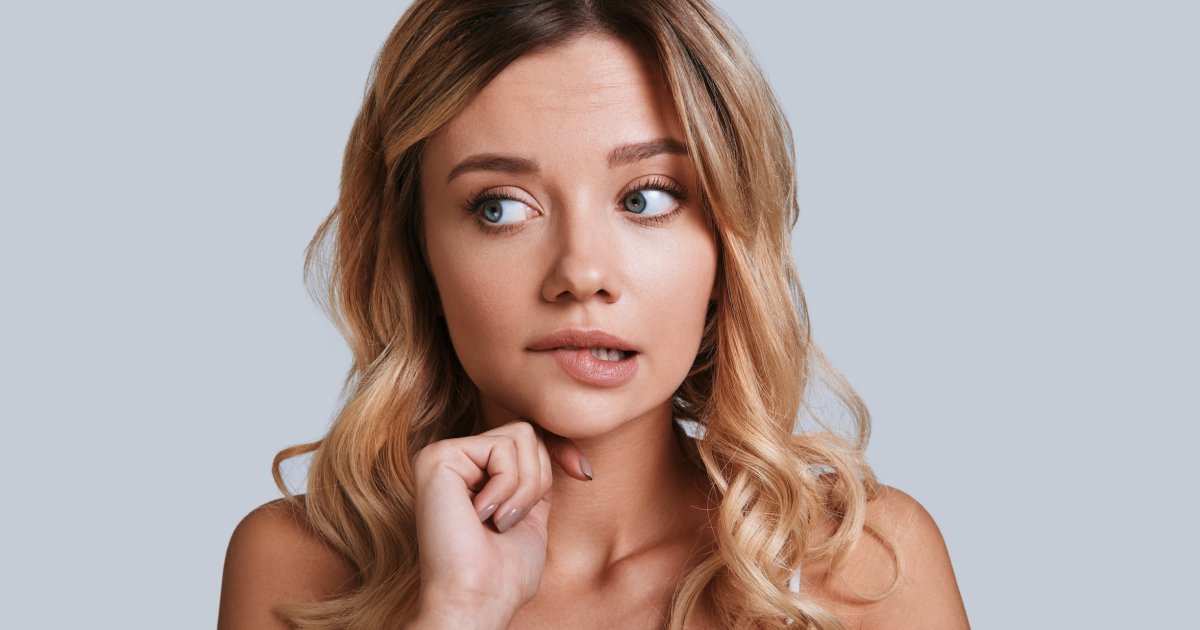 Jeune femme se mordant les lèvres, expression légèrement nerveuse