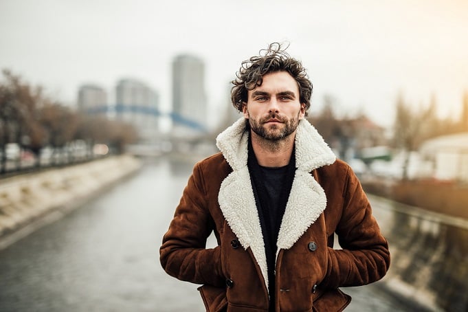 Homme élégant ajustant le bouton de sa manche, mains soignées et posture assurée