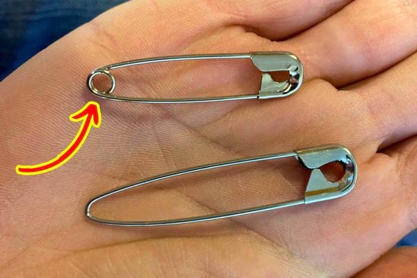 Main tenant une épingle à nourrice pour illustrer son utilisation en couture