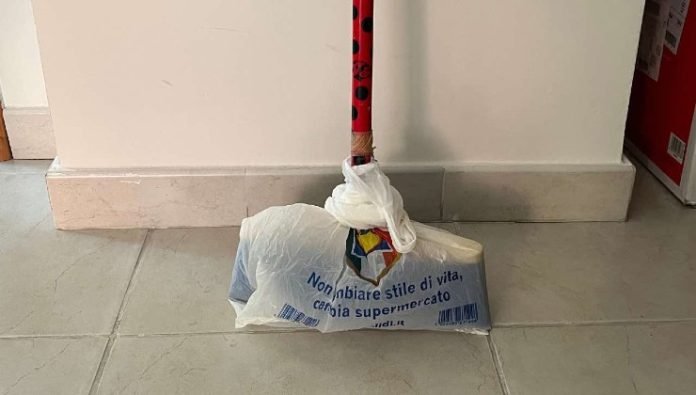 Balai traditionnel dont la tête est recouverte d'un sac plastique transparent